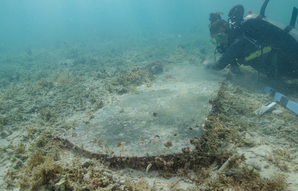 University of Miami graduate student Devon Fogarty examining John Greer's gravestone on the ocean floor