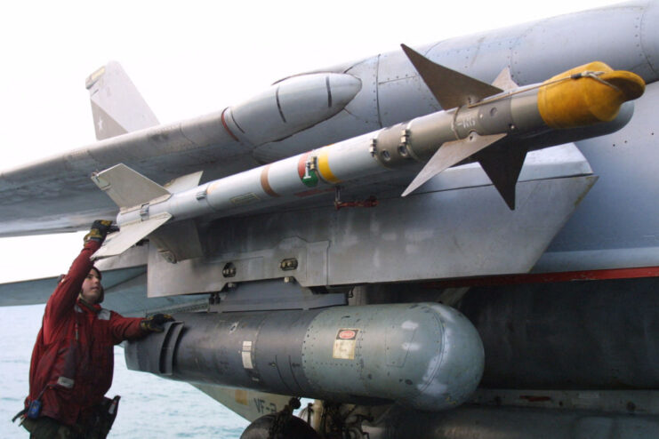 Sailor checking an AIM-9 Sidewinder on the underside of the wing of a Grumman F-14 Tomcat