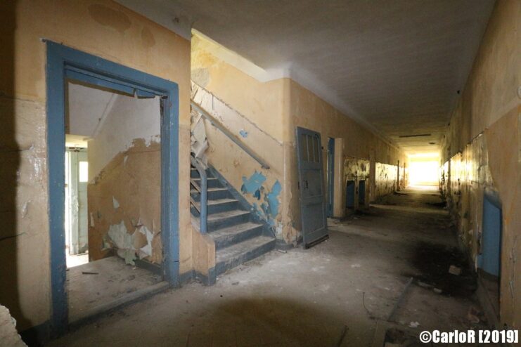 Empty hallway, with a stairway and doorframes along the walls