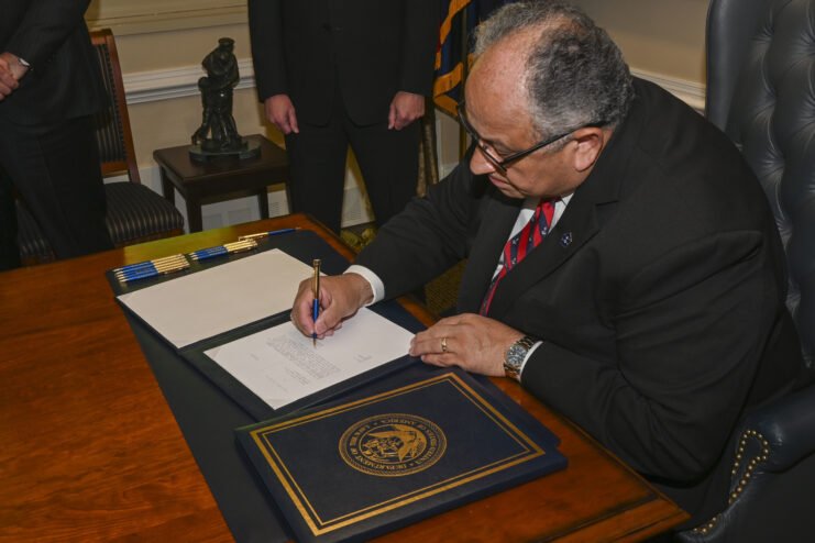 Carlos Del Toro signing a document at his desk