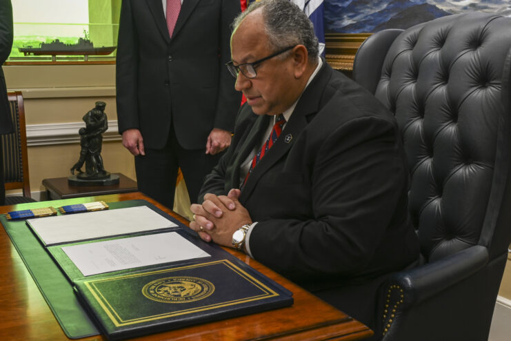 Carlos Del Toro reading a document laid out on his desk