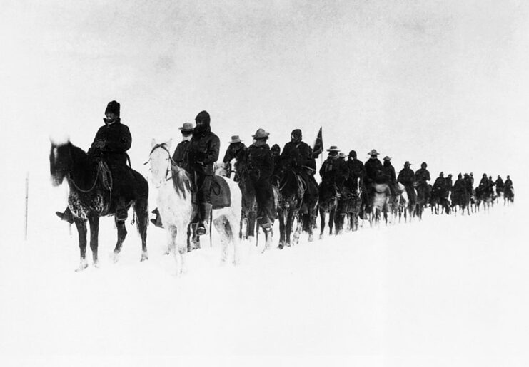 US Army cavalrymen riding on horseback through the snow