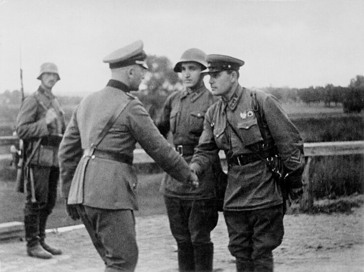 German and Soviet military officials shaking hands, while others watch in the background