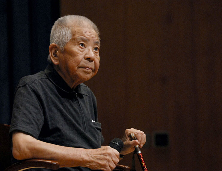 Tsutomu Yamaguchi sitting in a chair on stage