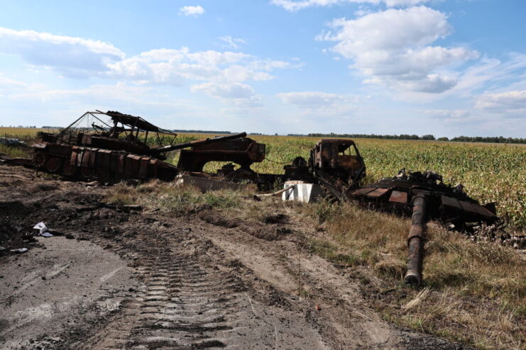 Destroyed tanks along the edge of a dirt road