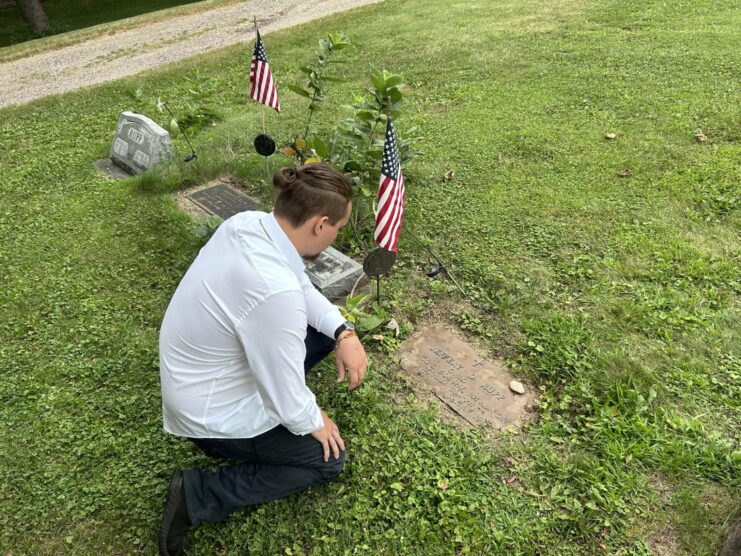 Hugo Booth kneeling at Jeffrey David Rupp's gravestone