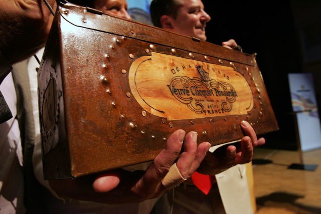 Auctioneer holding a wooden box containing champagne